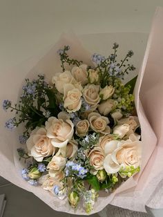 a bouquet of white roses and blue flowers in a paper wrapper on a table