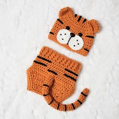 a crocheted tiger hat and diaper cover are laying on a white surface