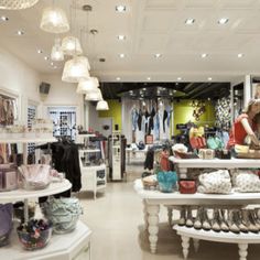 the inside of a clothing store with lots of shoes and bags on display in it