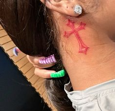 a woman with ear piercings has a cross tattoo on her left side behind her ear