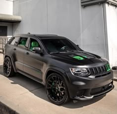 a gray jeep parked in front of a white building with green lettering on the side