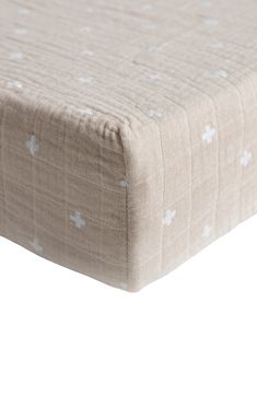 a close up view of the side of a bed with white stars on it and a light brown cover