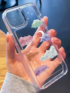 a hand holding a clear case with clouds and stars on it