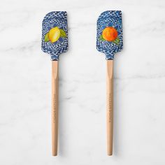 two wooden spatulas decorated with fruit on them sitting on a marble counter top