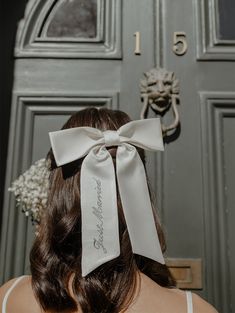 the back of a woman's head wearing a white ribbon with a name on it