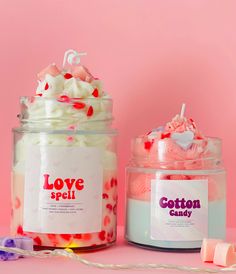 two jars filled with pink and white frosting next to each other on a pink surface