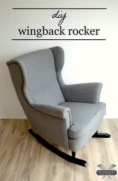 a gray rocking chair sitting on top of a hard wood floor next to a white wall