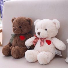 two teddy bears sitting next to each other on a white chair with a red heart