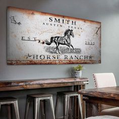 an old metal sign hangs on the wall above a wooden table and bar stools