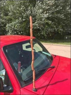 a red car with a stick sticking out of it's windshield