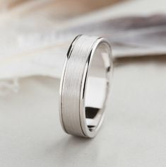 a white gold wedding ring on top of a table