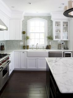 a white kitchen with marble counter tops and stainless steel stove top oven, dishwasher, and sink