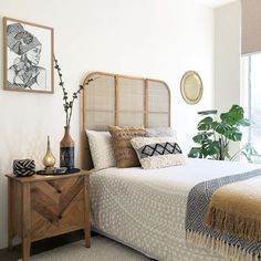 a bedroom with a bed, side table and potted plant on the nightstand next to it