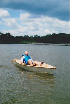 an older man is sitting in a small boat on the water with his feet propped up