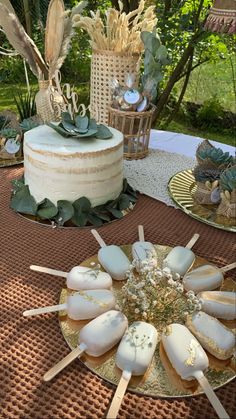 a table topped with cake pops covered in frosting next to other desserts and decorations