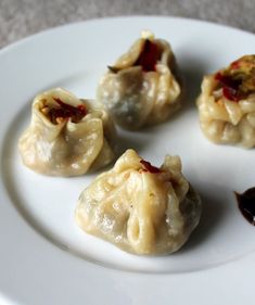 four dumplings with sauce on a white plate