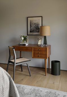 a bedroom with a desk, chair and lamp on it's side table in front of the bed