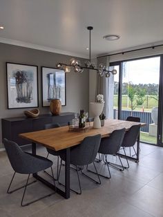 a dining room table with chairs and pictures on the wall behind it in front of a sliding glass door