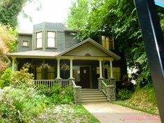 a small house is shown in the middle of some trees and bushes, with stairs leading up to the front door