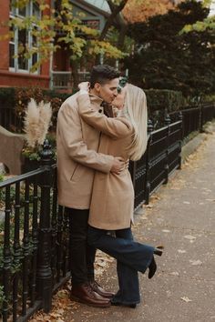 a man and woman standing next to each other near a fence