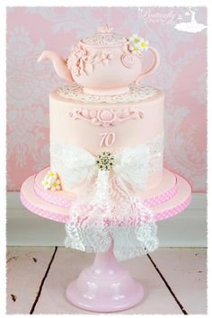 a pink and white cake with a teapot on top