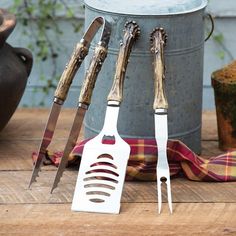 three kitchen utensils sitting on top of a wooden table next to a pot