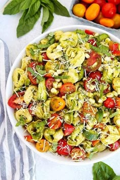 a white bowl filled with lots of food next to tomatoes and other vegetables on top of a table