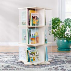 a white book shelf with books on it and a potted plant in the corner