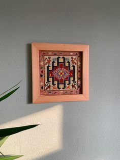 a wooden frame hanging on the wall above a potted plant