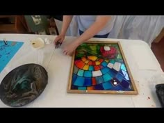 a woman is working on a stained glass piece