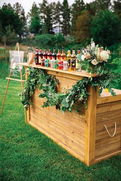 an outdoor bar with bottles of alcohol on it and greenery hanging from the top