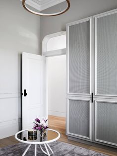 a living room with white walls and grey carpeted flooring is pictured in this image