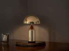 a table lamp sitting on top of a wooden table next to a glass cup and bottle