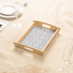 an empty tray sitting on top of a table next to wine glasses and silverware