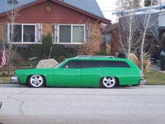 a green station wagon parked in front of a house