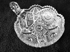 an ornate glass dish on a black cloth with silver trimmings and decorative designs