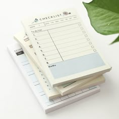 three sheets of paper stacked on top of each other next to a potted plant