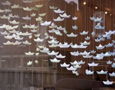 there are many paper birds hanging in the window