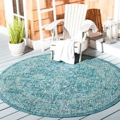 an outdoor area rug with two chairs and a potted plant