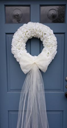 a wreath with white flowers is hanging on a blue door