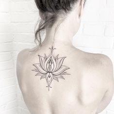 the back of a woman's neck with a lotus tattoo on her left shoulder