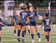 two women soccer players are jumping up in the air to congratulate each other