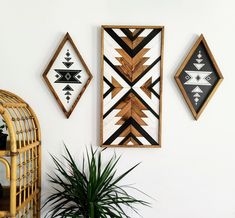 three framed art pieces hanging on the wall next to a potted plant and wicker basket