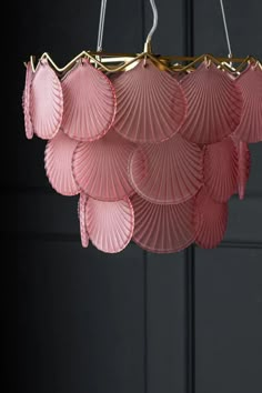 a pink chandelier hanging from the ceiling with lots of fan shaped petals on it