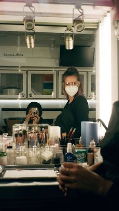 two people in a kitchen with masks on their faces and one person taking a selfie