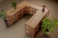 a wooden bench sitting next to a potted plant on top of a brown floor