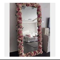 a mirror that has flowers on it in front of a room with a couch and table