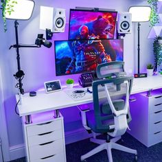 a desk with a computer and speakers on it in front of a wall mounted movie poster