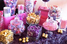 a table topped with lots of candy and candies on top of a purple cloth