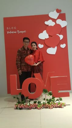 a man and woman standing in front of a love sign